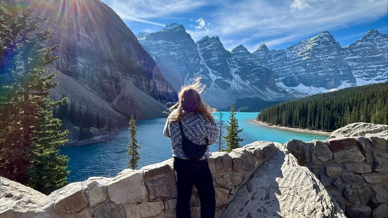 En kvinna står på en klippvägg med utsikt över en sjö.