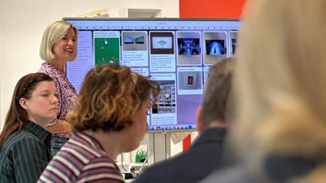 En grupp människor som står framför en datorskärm.