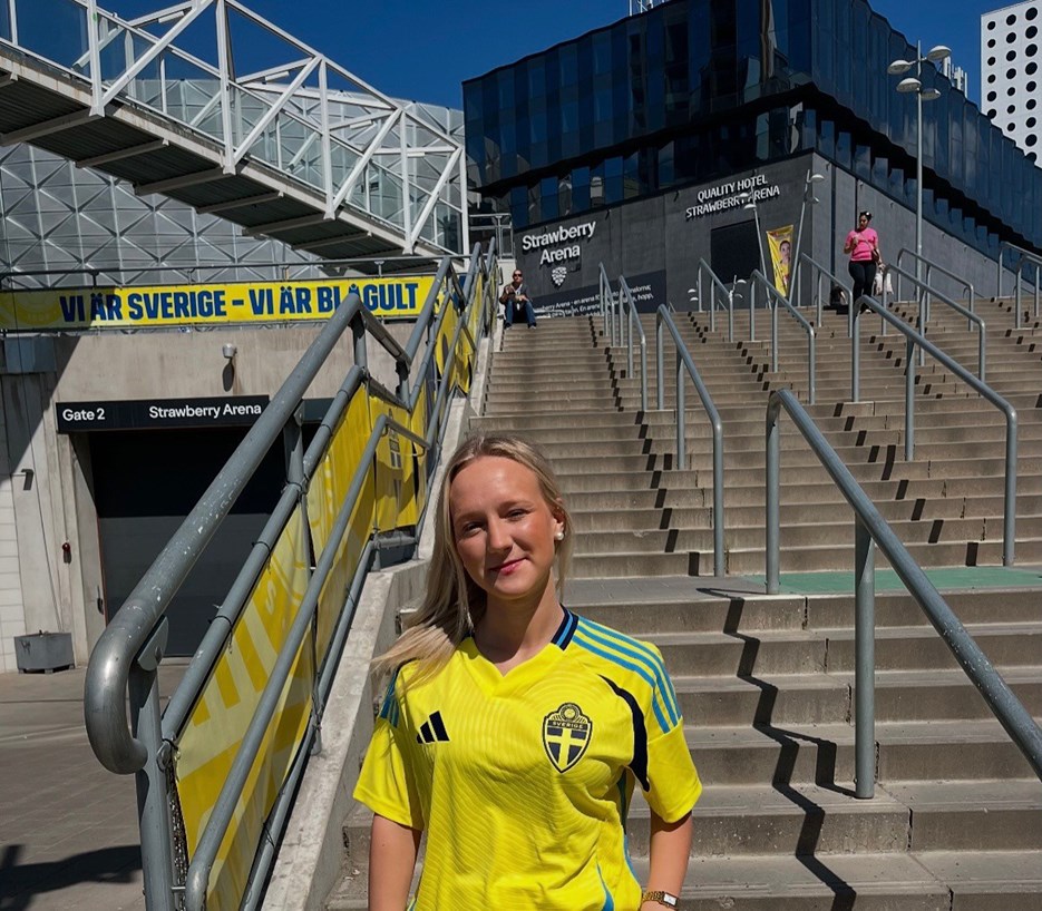En kvinna i landslagströja står på en trappa.