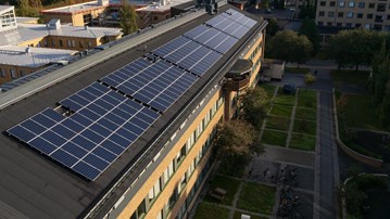En bild med ett av universitetets byggnader med solceller installerade på taket
