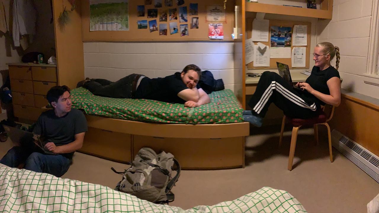 Tre personer umgås i ett studentrum. En sitter på golvet, en ligger på sängen och en sitter på en stol.