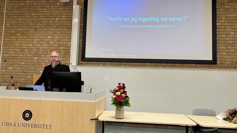 Peter Johansson står vid ett podium med en powerpointbild bakom sig där det står "Varför vet jag ingenting om samer?"