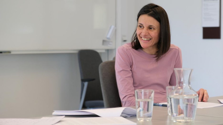 Vladislava sitter vid ett bord med vattenglas och ler.