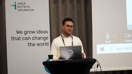 En man står på ett podium med en bärbar dator framför sig.