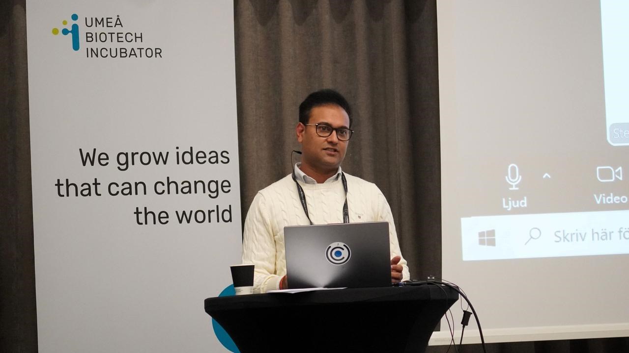 En man st&aring;r p&aring; ett podium med en b&auml;rbar dator framf&ouml;r sig.