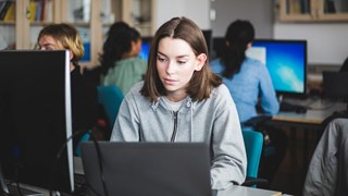 Flicka framför dator