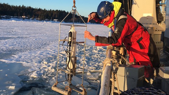 en person hanterar provtagningsutrustning vid relingen av ett fartyg
