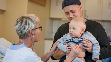 Pappa och barn på besök hos distriktssköterska