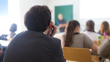 Ungdomar i klassrum lyssnar på lärare som undervisar.