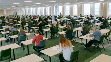 En grupp studenter sitter i en tentamensal och skriver en tentamen.