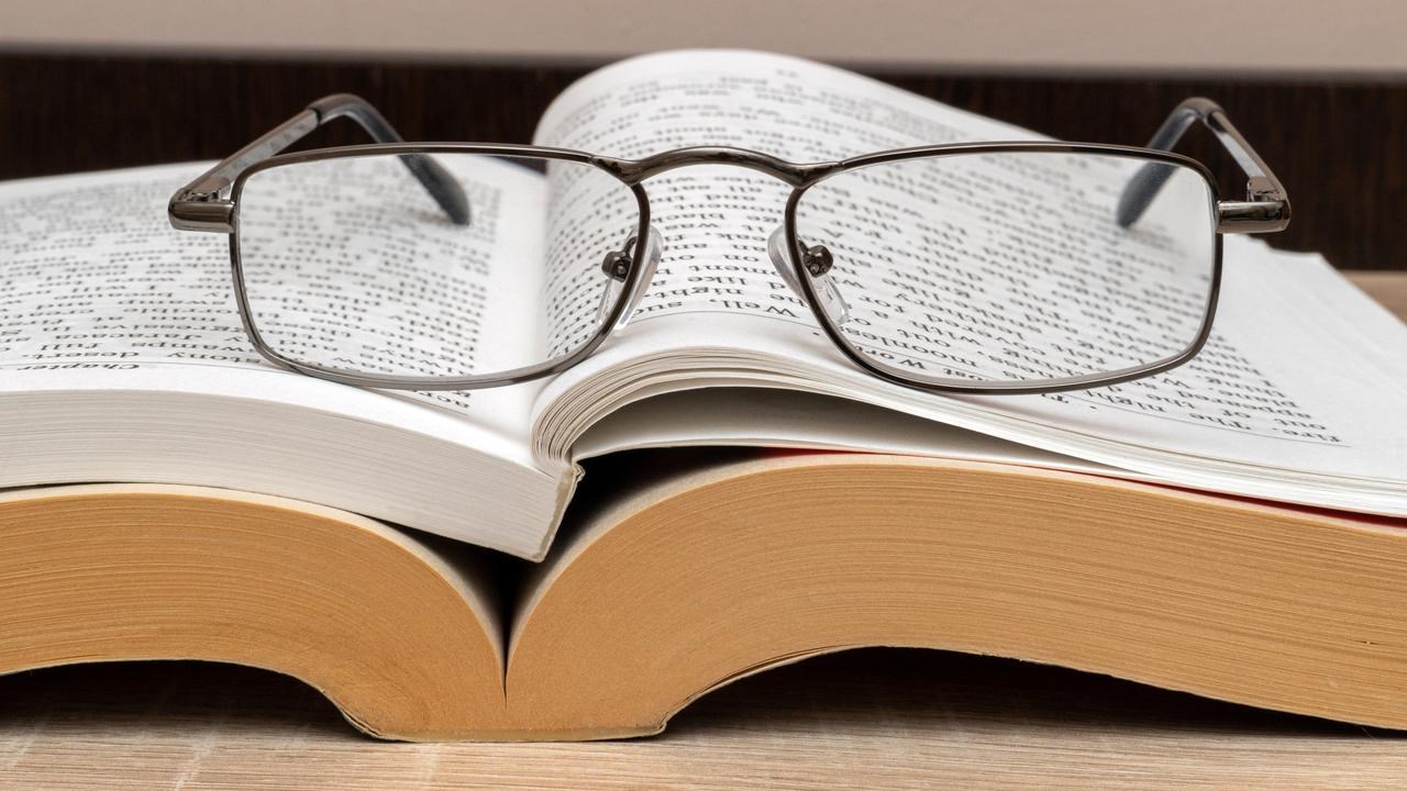 Läsglasögon på en uppslagen bok.