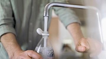 Häller vatten från kran i flaska