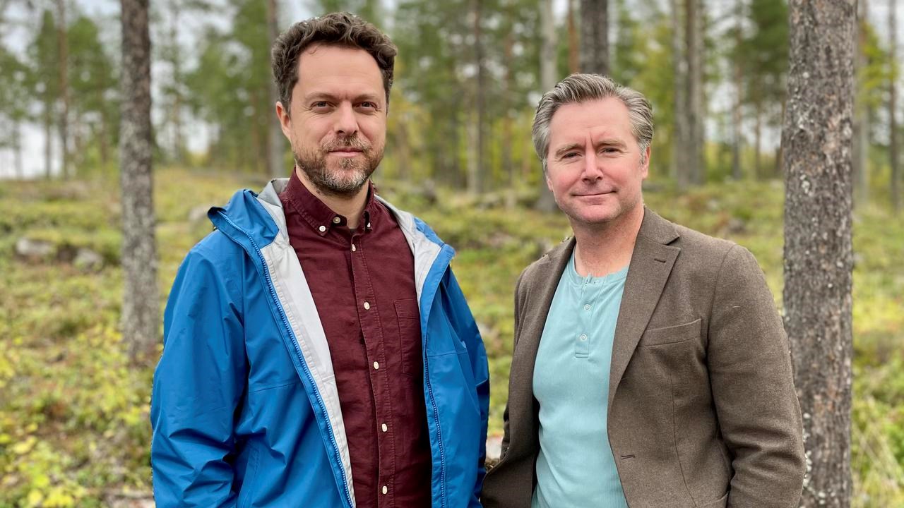 Två män som står bredvid varandra i en skog.