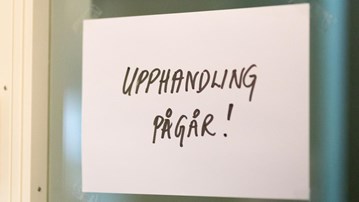 Textad skylt med ordet "Upphandling pågår" uppsatt vid en dörr.