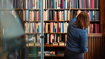 Kvinna letar böcker i ett bibliotek.