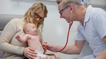 Läkaren Magnus Domellöf lyssnar på hjärtat på ett litet barn.