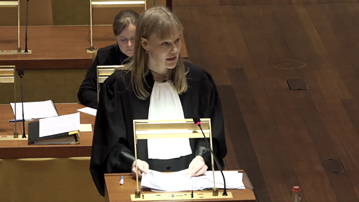 En kvinna står vid ett podium i ett rum.