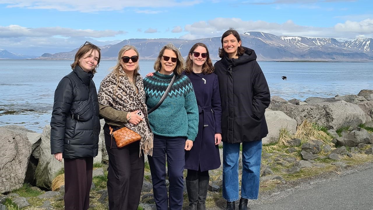 Gruppbild taget på Island med vatten och berg i bakgrunden.