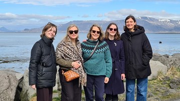 Gruppbild taget på Island med vatten och berg i bakgrunden.