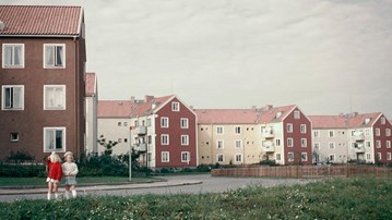 Två flickor står framför en rad med hus.