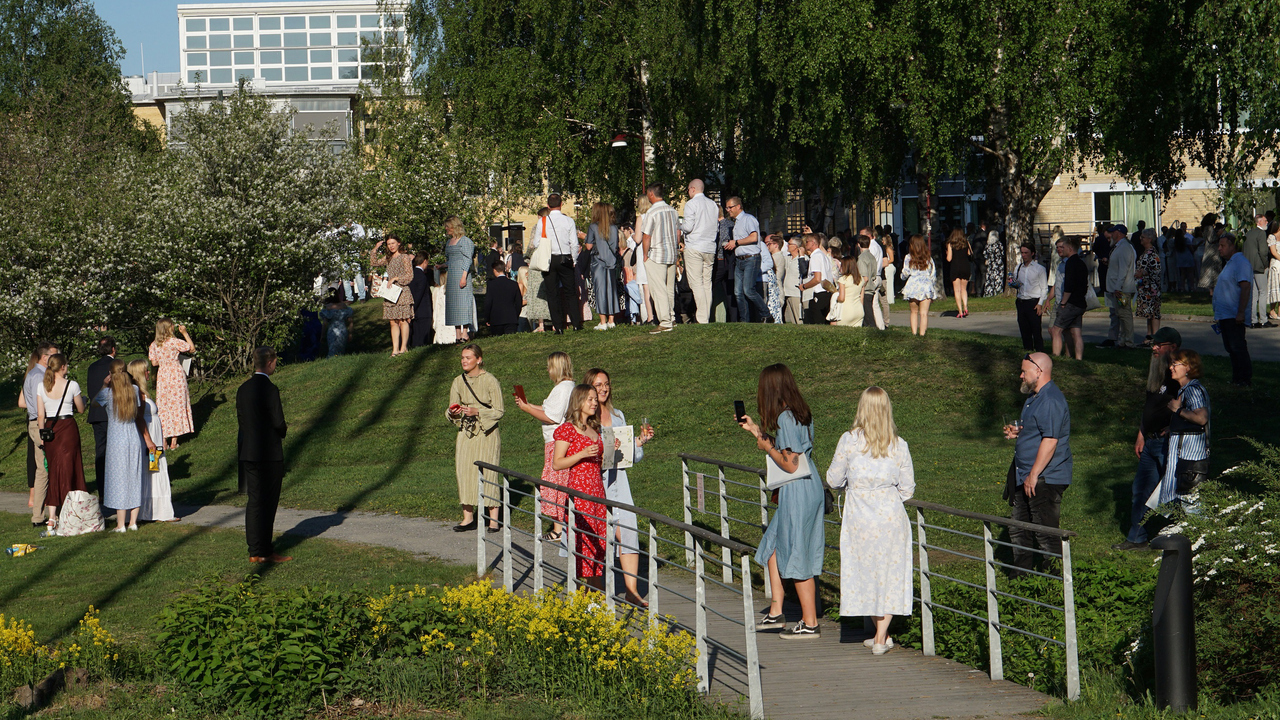 Studenter minglar utomhus i solen i samband med Handelsh&ouml;gskolans diplomeringsceremoni.