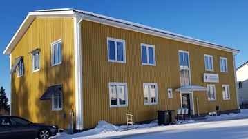 En bil parkerad framför en gul byggnad.