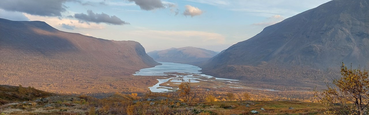 Vy över vattendrag genom fjällandskap.
