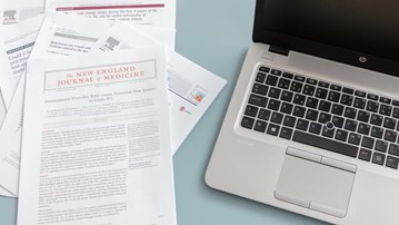 Vetenskapliga artiklar bredvid bärbar dator