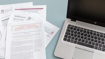 Vetenskapliga artiklar bredvid bärbar dator