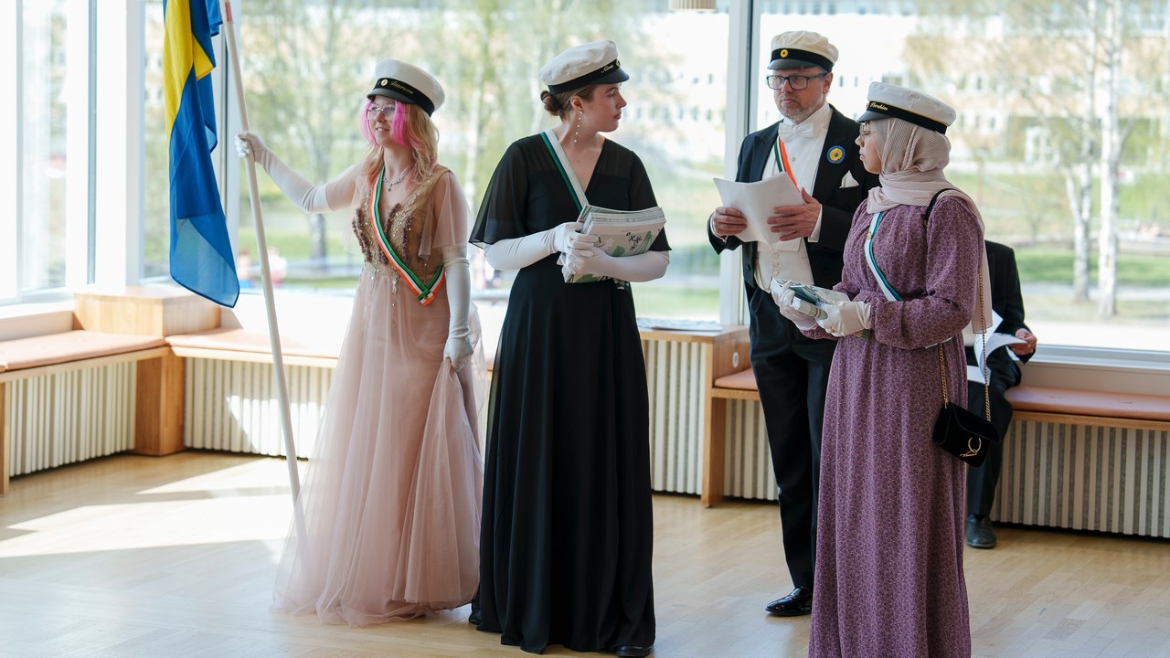 Studentmarskalkar står med flagga och delar ut programademiska högtiderStudenter
