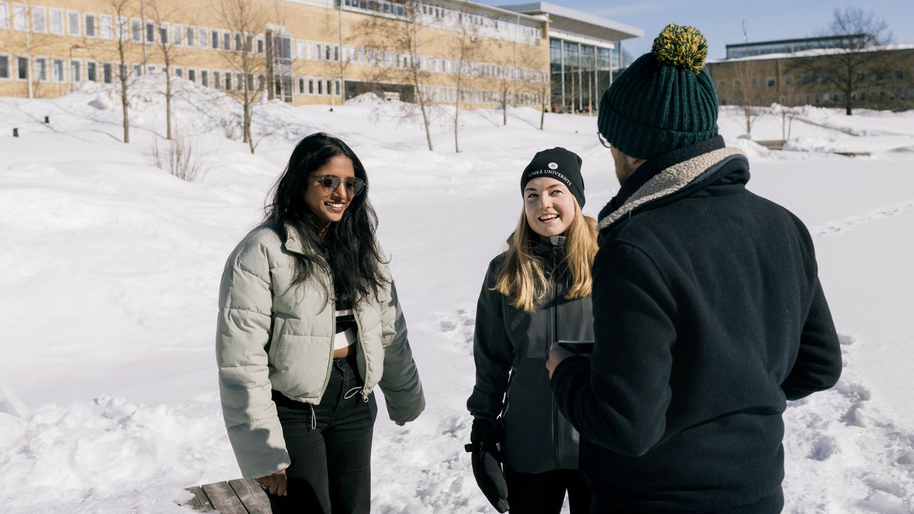 Internationella studenter vid dammen snön med Lindellhallen i bakgrunden.
