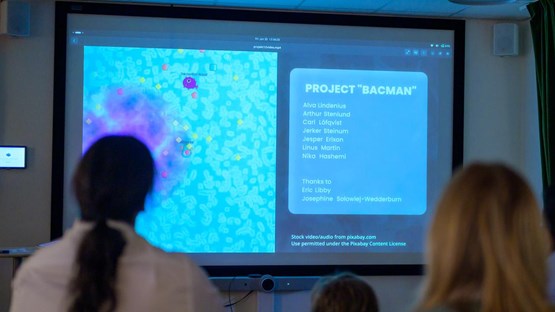 A group of people sitting in front of a projector screen.