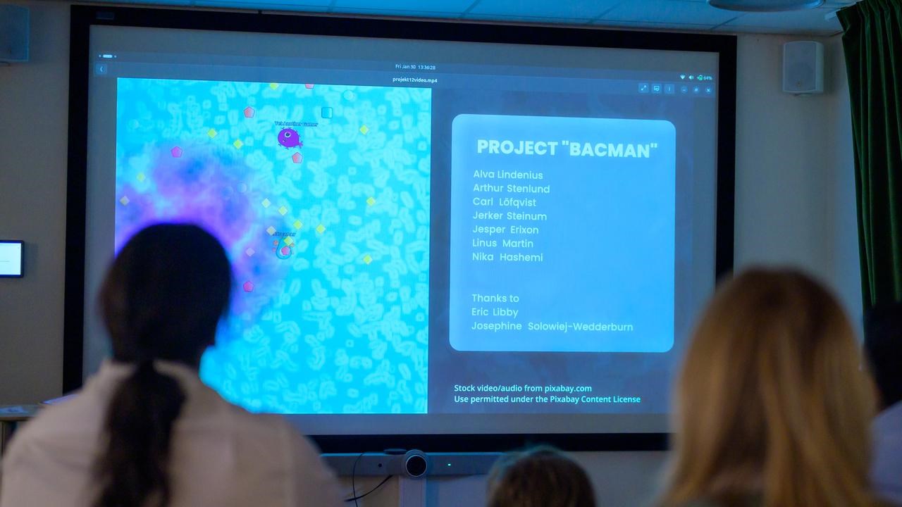 A group of people sitting in front of a projector screen.