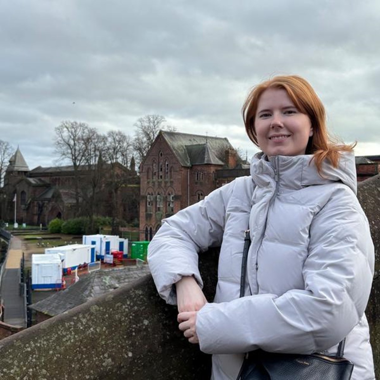 En kvinna st&aring;r p&aring; en bro med armarna i kors.