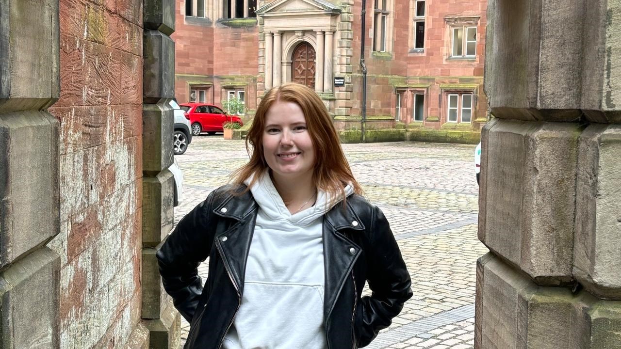 En kvinna står framför en grind.