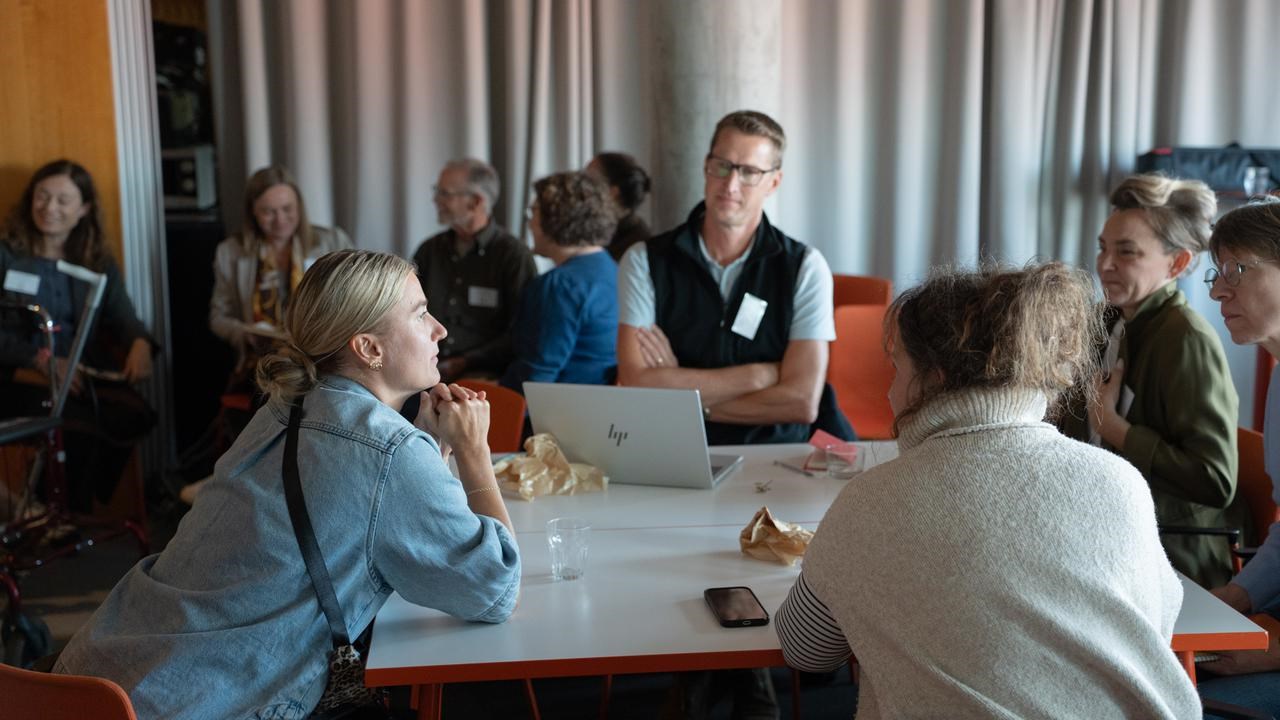 Personer sitter runt ett bord och diskuterar.