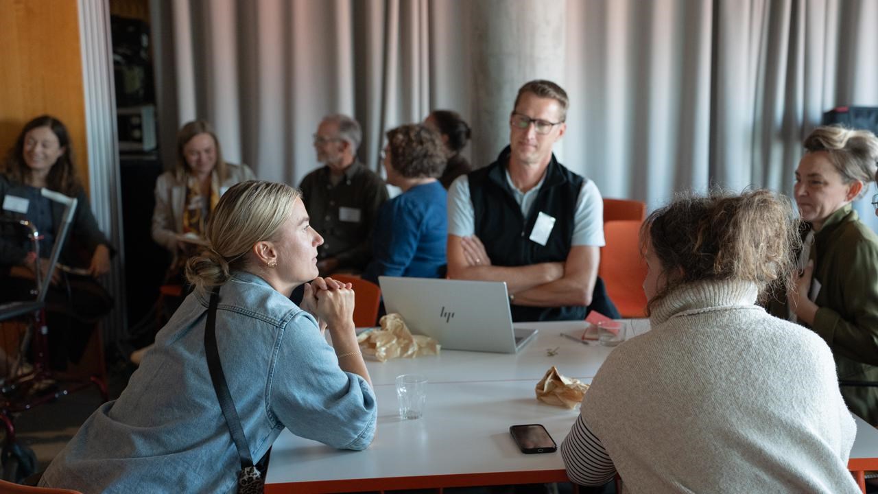 Personer sitter runt ett bord och diskuterar.