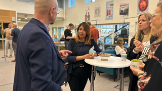 4 people around a table, standing, discussing and drinking coffee