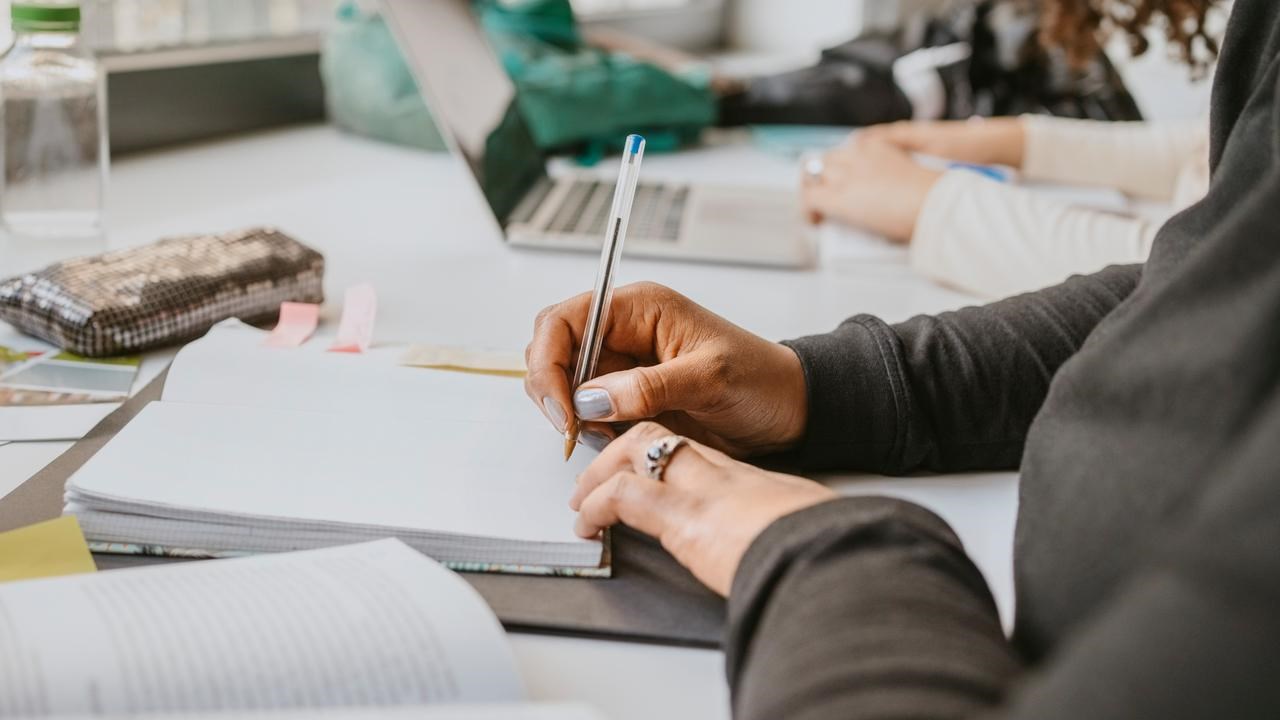 Person som studerar och antecknar i ett block.