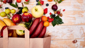 Frukt och bär hällda ur en papperspåse på ett bord. Nyttiga livsmedel.