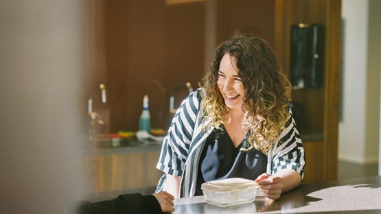 kvinna i randig blus sitter vid ett bord och skrattar