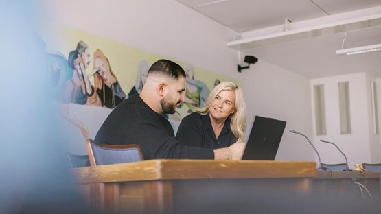 Två personer vid ett bord framför en dator