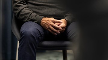 Händer o knän på man i gruppterapi