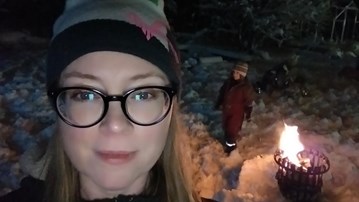 Linda Lundmar, föreståndare vid den arktiska forskarskolan vid Arcum, är utomhus vid en grillkorg med sitt barn en mörk vinterkväll