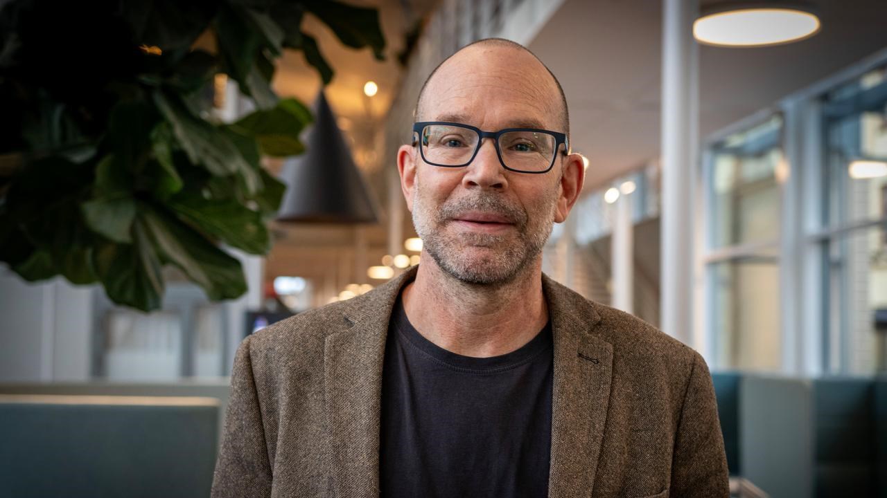 En man med glasögon står på ett kontor.