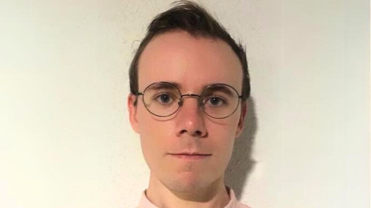 Porträttbild av S.C, med kort brunt hår och runda glasögon