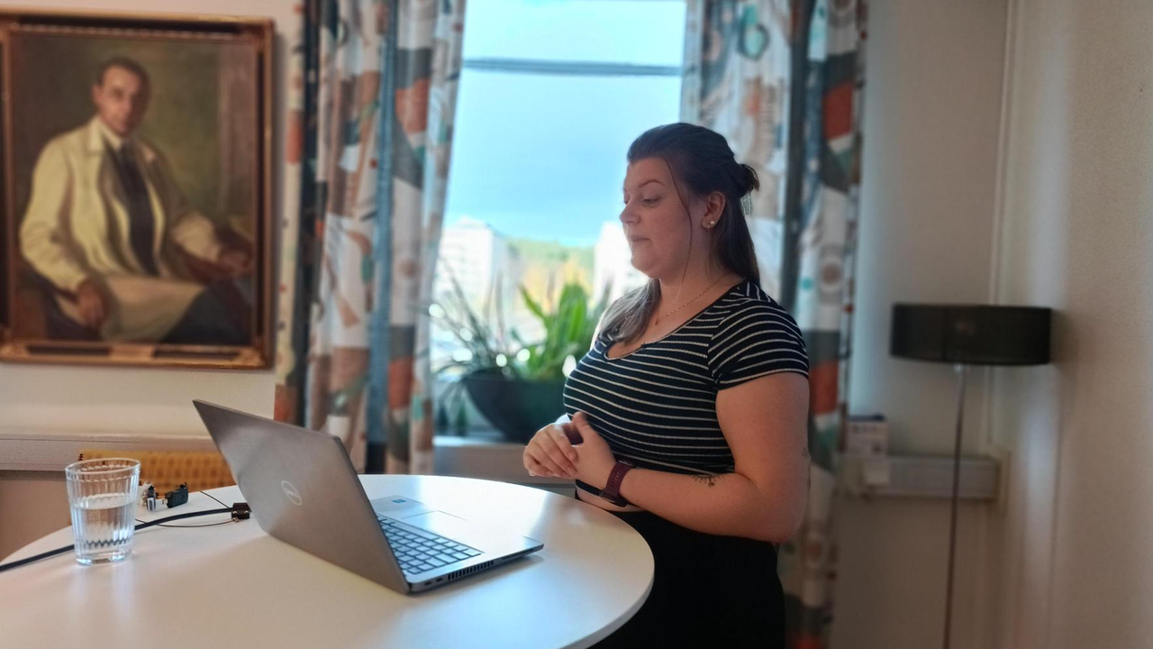Rebecca Tapper st&aring;r vid en laptop och presenterar sitt forskningsprojekt