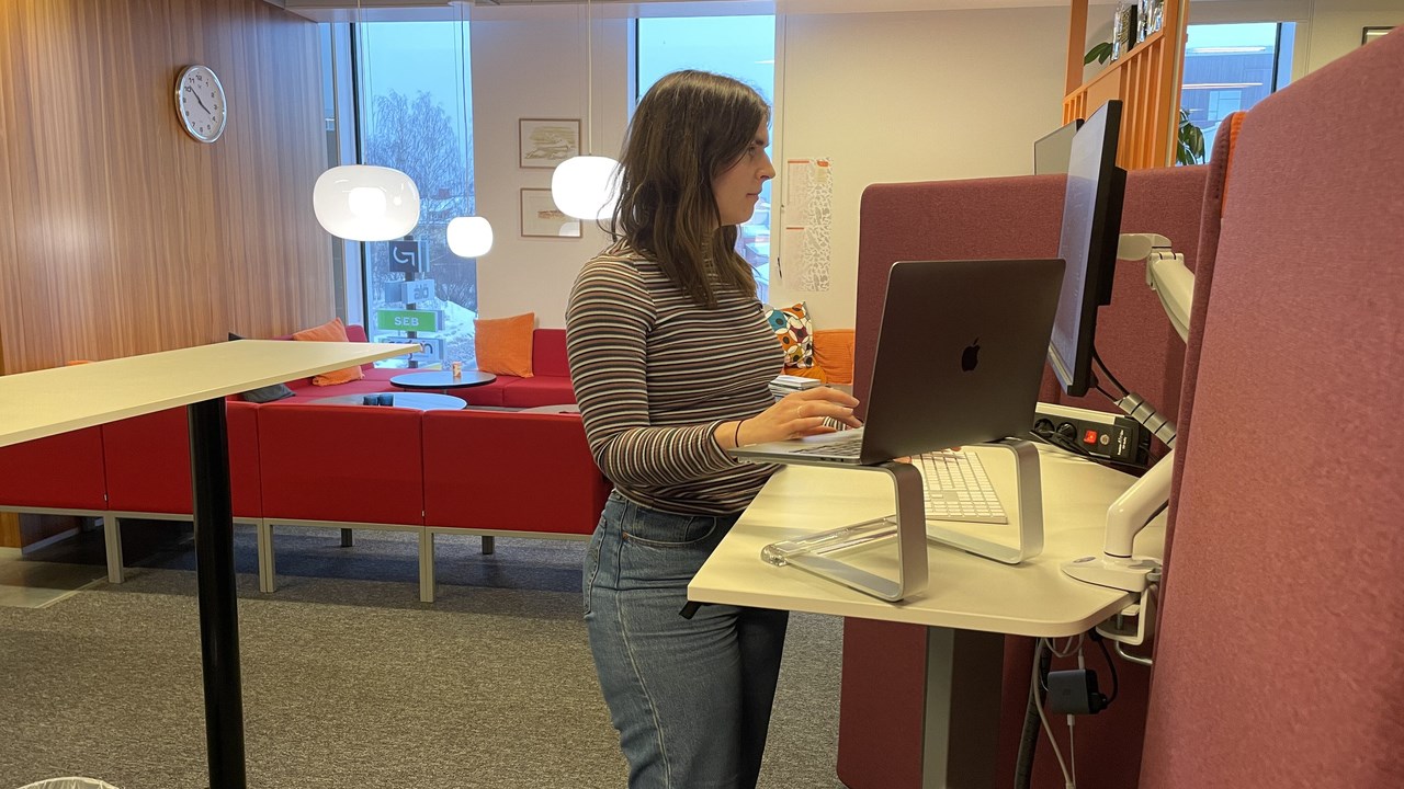 Elin Lindén stående vid sitt skrivbord i kontorsmiljön på konsultföretaget Ecogain.