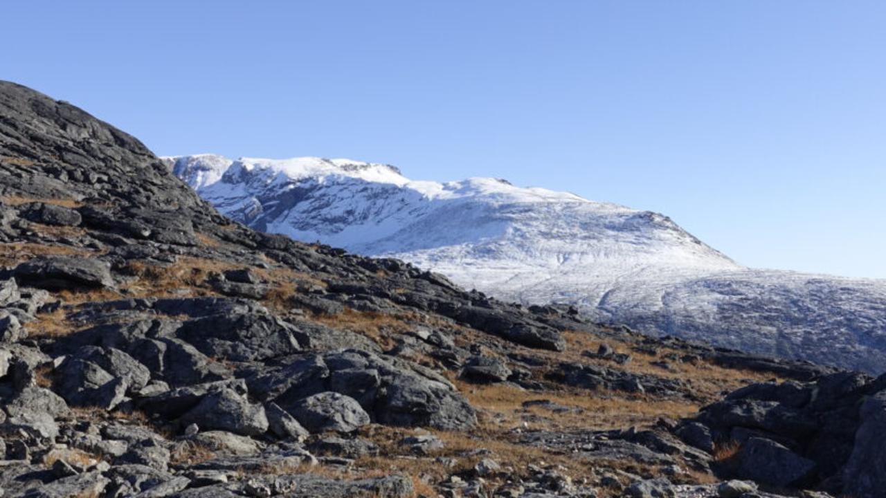 En stenig sluttning med ett snötäckt berg i bakgrunden.