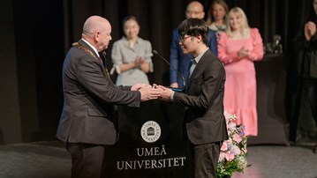 The Vice-Chancellor hands over a congratulatory scroll to a graduating master's student at Umeå University.